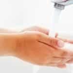 Child is washing hands under running water.